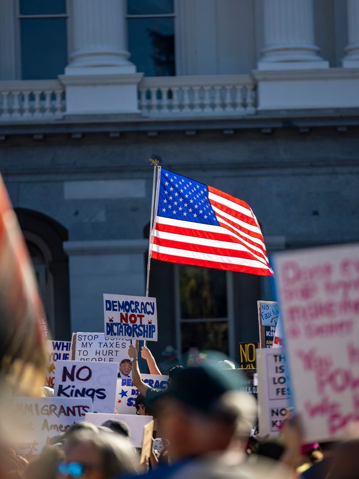 A flag and hand-lettered signs raised at a rally outside a statehouse
