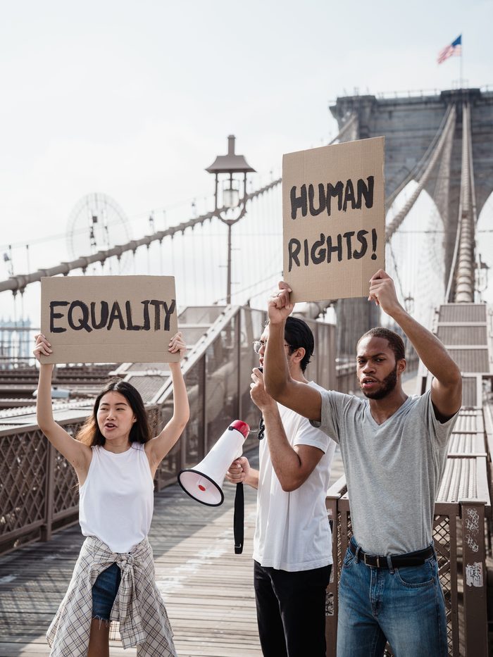 Demonstrators on a bridge holding signs reading Equality and Human Rights