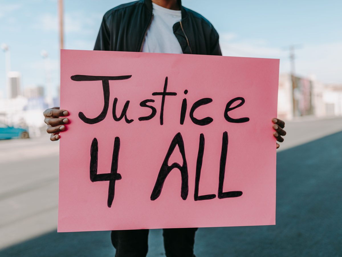 A person holding a hand-lettered sign reading Justice 4 All