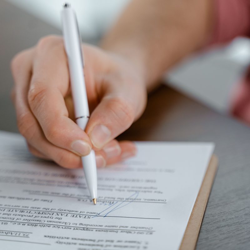 A person signing a printed form with a pen