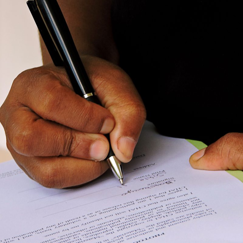Close view of a hand signing a printed consent form